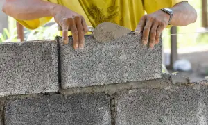 Murarz układa bloczki betonowe fundamentowe, tworząc solidną podstawę.