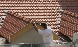 Pracownik mierzy drewnianą konstrukcję dachu podczas obróbki dachu wiatrownica.