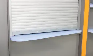 Zastanawiasz się, jaki przekrój kabel do rolet zewnętrznych? Widzisz tu roletę z szarymi lamelami i jasnoniebieski parapet.