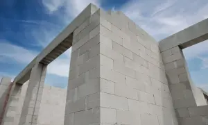 Ściany domu w budowie, wzniesione z pustaków z betonu komórkowego, pod błękitnym niebem.