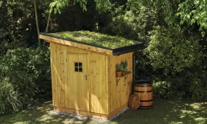 Drewniana szopa z zielonym dachem, obok beczka. Idealny projekt budowa szopy drewnianej krok po kroku.