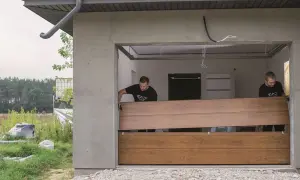 Dwóch mężczyzn montuje nowe panele, realizując wymianę okleiny na bramie garażowej.