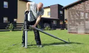 Mężczyzna montuje śruby fundamentowe za pomocą wiertnicy. Solidne śruby fundamentowe zapewniają stabilność konstrukcji.