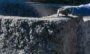 Ręka w rękawicy wygładza świeży beton C30/37. Sprawdź aktualną beton c30/37 cena.