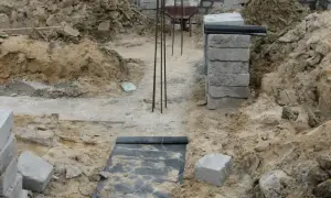 Budowa domu w toku. Widoczne wykopy, zbrojenie i materiały budowlane, tworzące fundamenty domu.