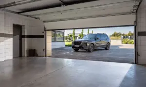 Nowa, nowoczesna brama garażowa strzela przy otwieraniu, odsłaniając luksusowego SUV-a na podjeździe.