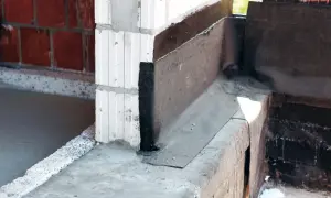 Warstwa papy na fundamencie chroni przed wilgocią. Widoczny narożnik z izolacją.