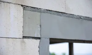 Fragment ściany z bloczków z widocznymi otworami dekompresyjnymi w oknach, przygotowanymi do montażu.