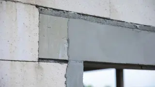 Fragment ściany z bloczków z widocznymi otworami dekompresyjnymi w oknach, przygotowanymi do montażu.