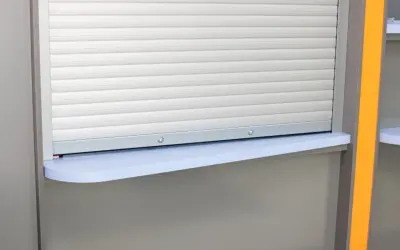 Zastanawiasz się, jaki przekrój kabel do rolet zewnętrznych? Widzisz tu roletę z szarymi lamelami i jasnoniebieski parapet.