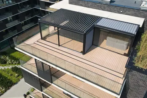 Nowoczesny taras na dachu z papy, z przeszklonym pawilonem i pergolą. Drewniana podłoga i szklane balustrady tworzą elegancką przestrzeń.