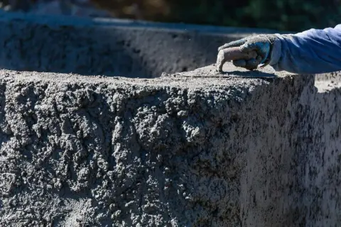 Ręka w rękawicy wygładza świeży beton C30/37. Sprawdź aktualną beton c30/37 cena.