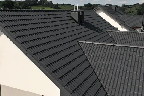 Nowoczesne domy z ciemnoszarą dachówką IBF. Dachy pokryte dachówką IBF tworzą spójną całość z zielonym krajobrazem.