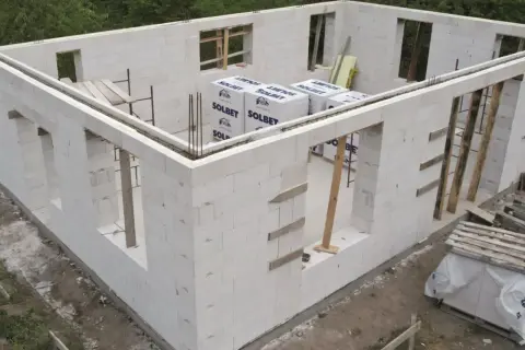 Budowa domu z bloczków SOLBET – najtańszy materiał na ściany. Widać zbrojenie i przygotowane otwory okienne.