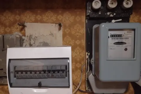 Stary licznik energii elektrycznej i nowoczesna rozdzielnica z bezpiecznikami, chroniąca przed przeciążeniem i zwarciem.