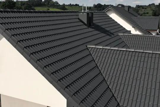 Nowoczesne domy z ciemnoszarą dachówką IBF. Dachy pokryte dachówką IBF tworzą spójną całość z zielonym krajobrazem.