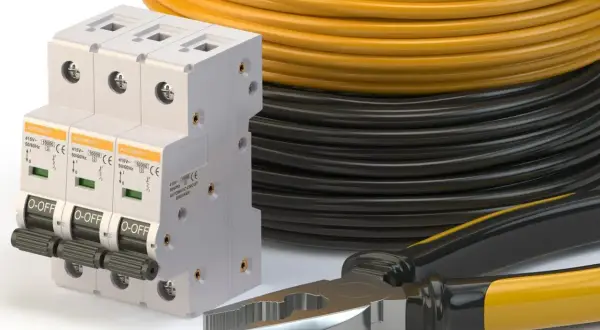 Wyłączniki nadprądowe, zwój żółtego i czarnego kabla oraz kombinerki. Idealne do instalacji, jaki kabel od skrzynki do domu 14kW?