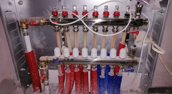 System ogrzewania podłogowego z rozdzielaczem. Widać tu m.in. ilu żyłowy kabel do termostatu pokojowego, zawory i rurki.