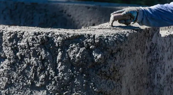Ręka w rękawicy wygładza świeży beton C30/37. Sprawdź aktualną beton c30/37 cena.