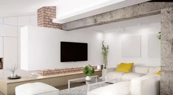 Nowoczesny salon z białym narożnikiem, telewizorem i ceglanym elementem architektonicznym, który pełni funkcję podciągu zamiast ściany nośnej.