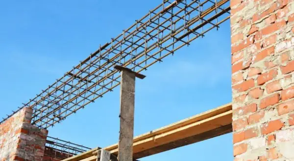 Siatka zbrojeniowa nadproża 3m, gotowa do zalania betonem, na tle błękitnego nieba i ceglanej ściany.