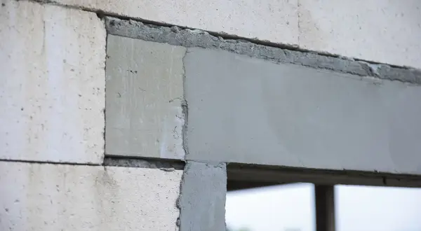 Fragment ściany z bloczków z widocznymi otworami dekompresyjnymi w oknach, przygotowanymi do montażu.