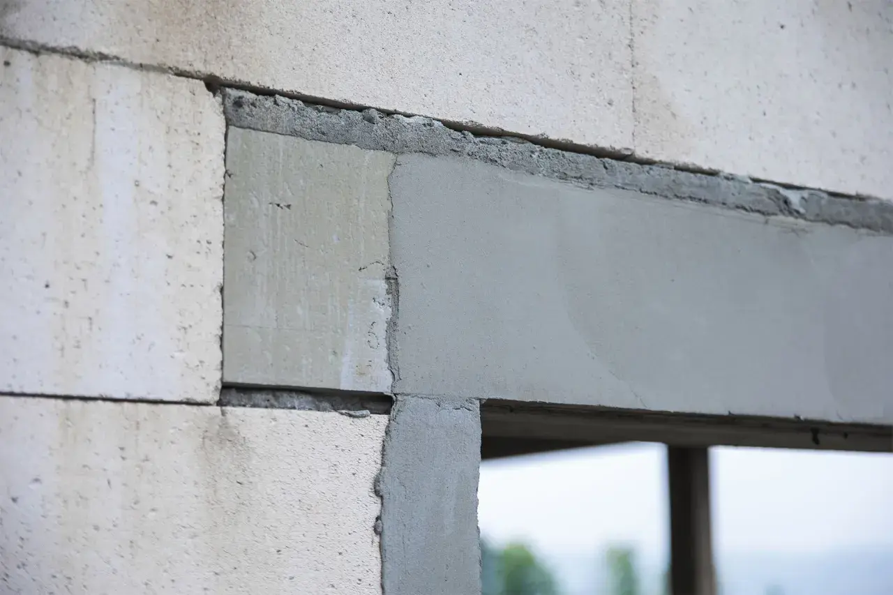 Fragment ściany z bloczków z widocznymi otworami dekompresyjnymi w oknach, przygotowanymi do montażu.