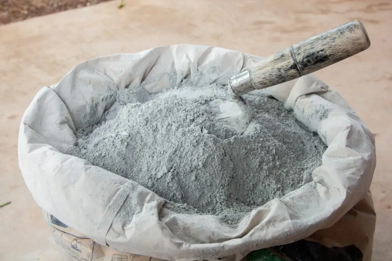 Worek z cementem i łopatką. Czas, ile schnie cement, zależy od wielu czynników, ale ten materiał jest gotowy do użycia.