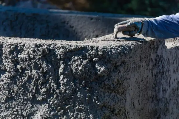 Ręka w rękawicy wygładza świeży beton C30/37. Sprawdź aktualną beton c30/37 cena.
